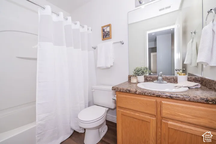Bathroom featuring a white tub, oval sink, wood-finish vanity, and a large mirror