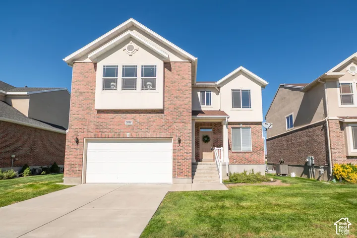 Brick and stucco exterior with multiple windows, an attached garage, a concrete driveway, and a front entry with steps