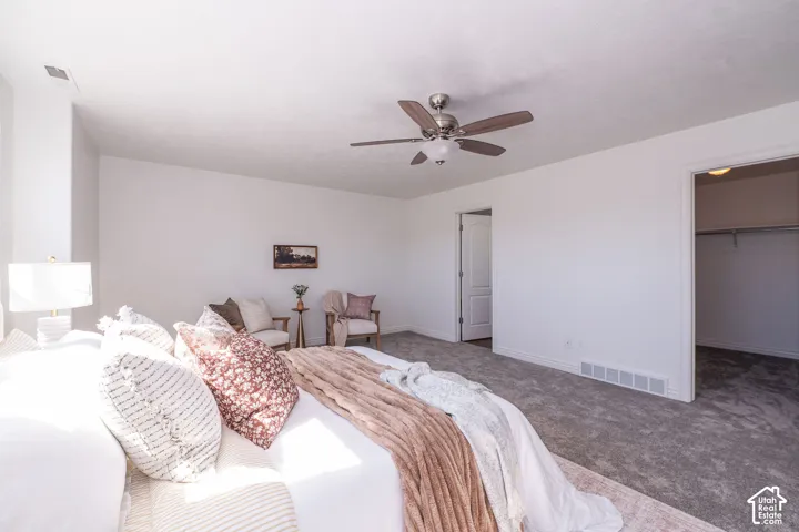 Carpeted bedroom with a ceiling fan, white baseboards, and a closet with a built-in rod
