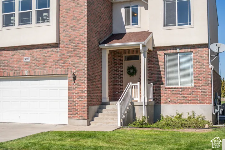 Brick and stucco exterior with multiple windows, an attached garage, and a covered entryway