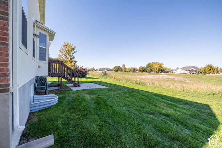 Expansive green lawn with a concrete patio and a wooden deck