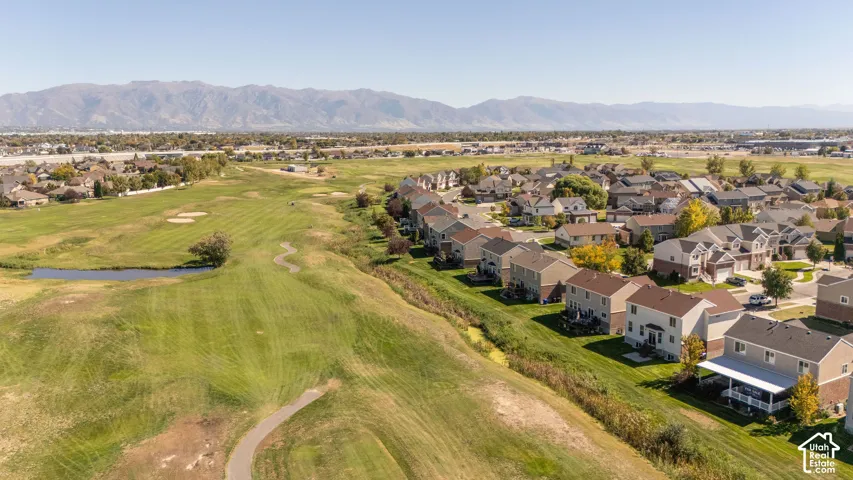 Residential properties bordering a manicured golf course, featuring established landscaping and a mountainous backdrop