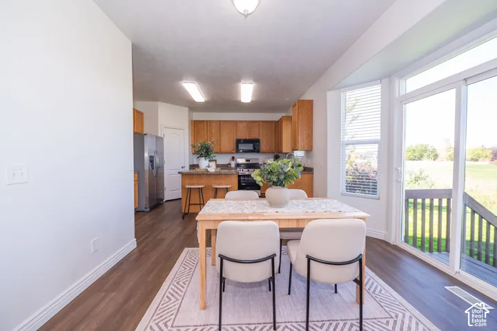 Wood-finish flooring, sliding glass door, recessed lighting, wood cabinetry, stainless steel refrigerator