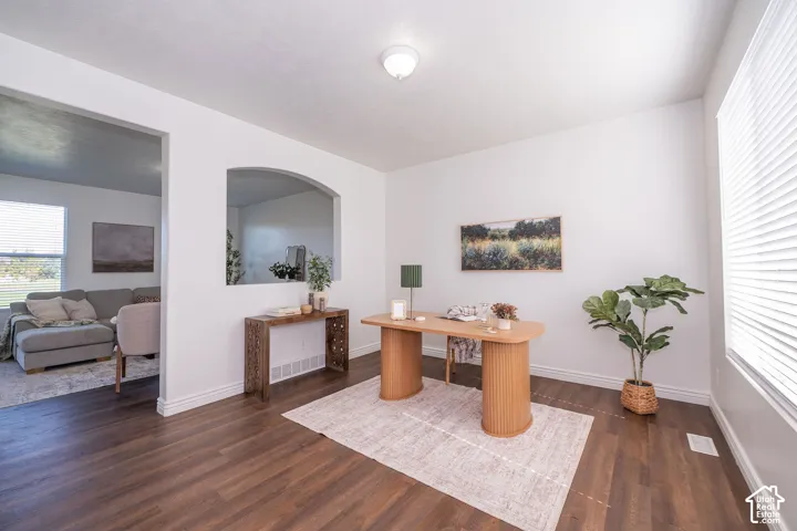 Wood-finish flooring, white walls, arched wall opening, and a window with blinds