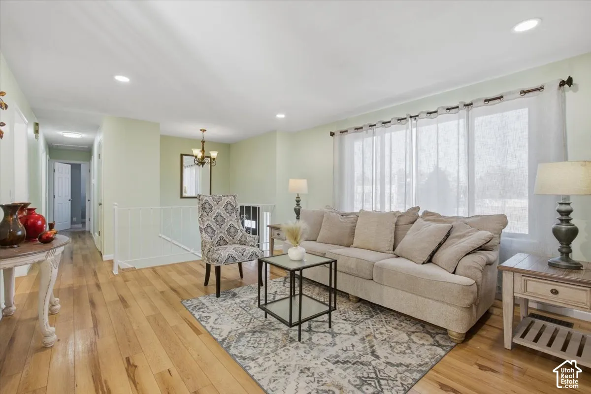 Hardwood-finish flooring, recessed ceiling lighting, prominent window wall, and a staircase with a white railing