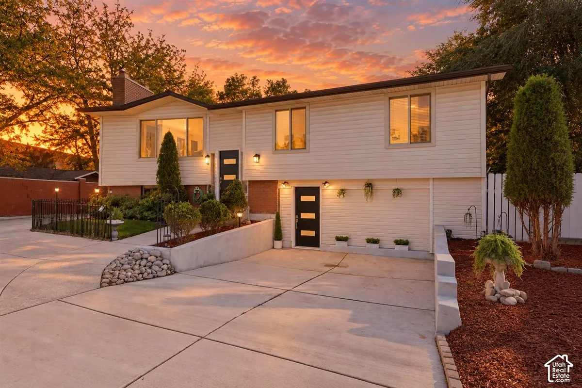 Split-level residence featuring light-colored siding, a multi-pane front door, and a paved driveway