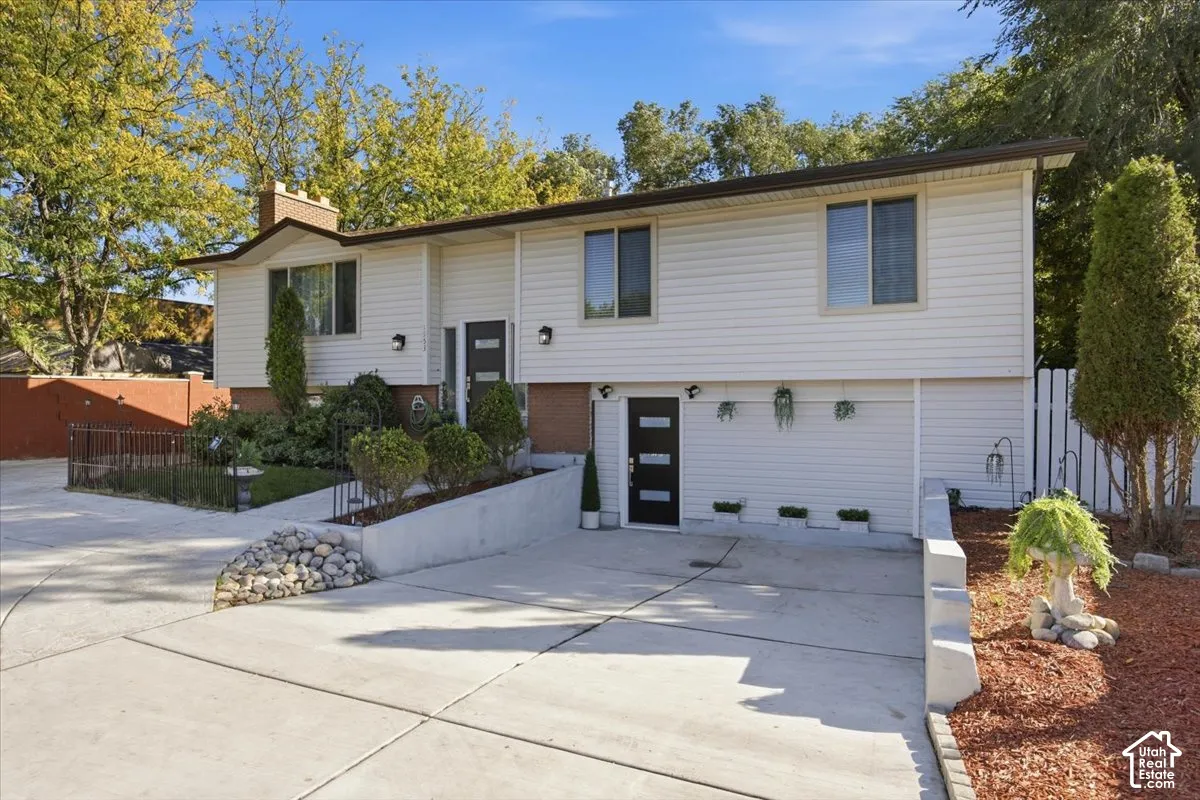 Split-level residence featuring white siding and dark trim
