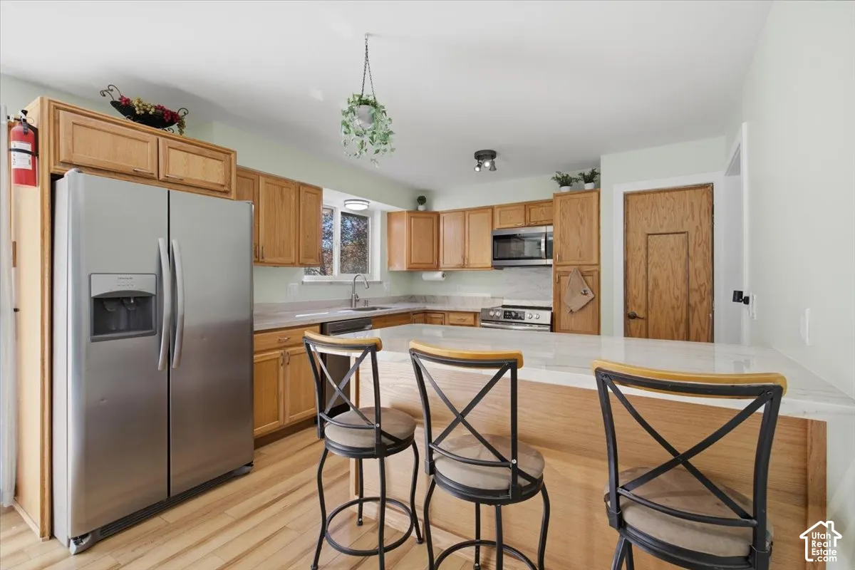 Kitchen featuring wood-finish cabinetry, stainless steel appliances, a breakfast bar, and light-toned countertops