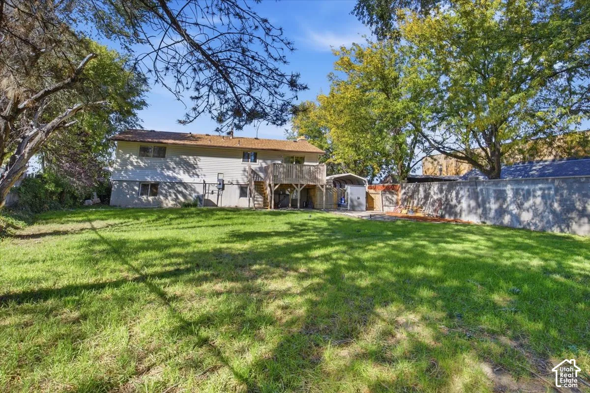Expansive backyard with a manicured lawn, mature trees, and a concrete perimeter wall