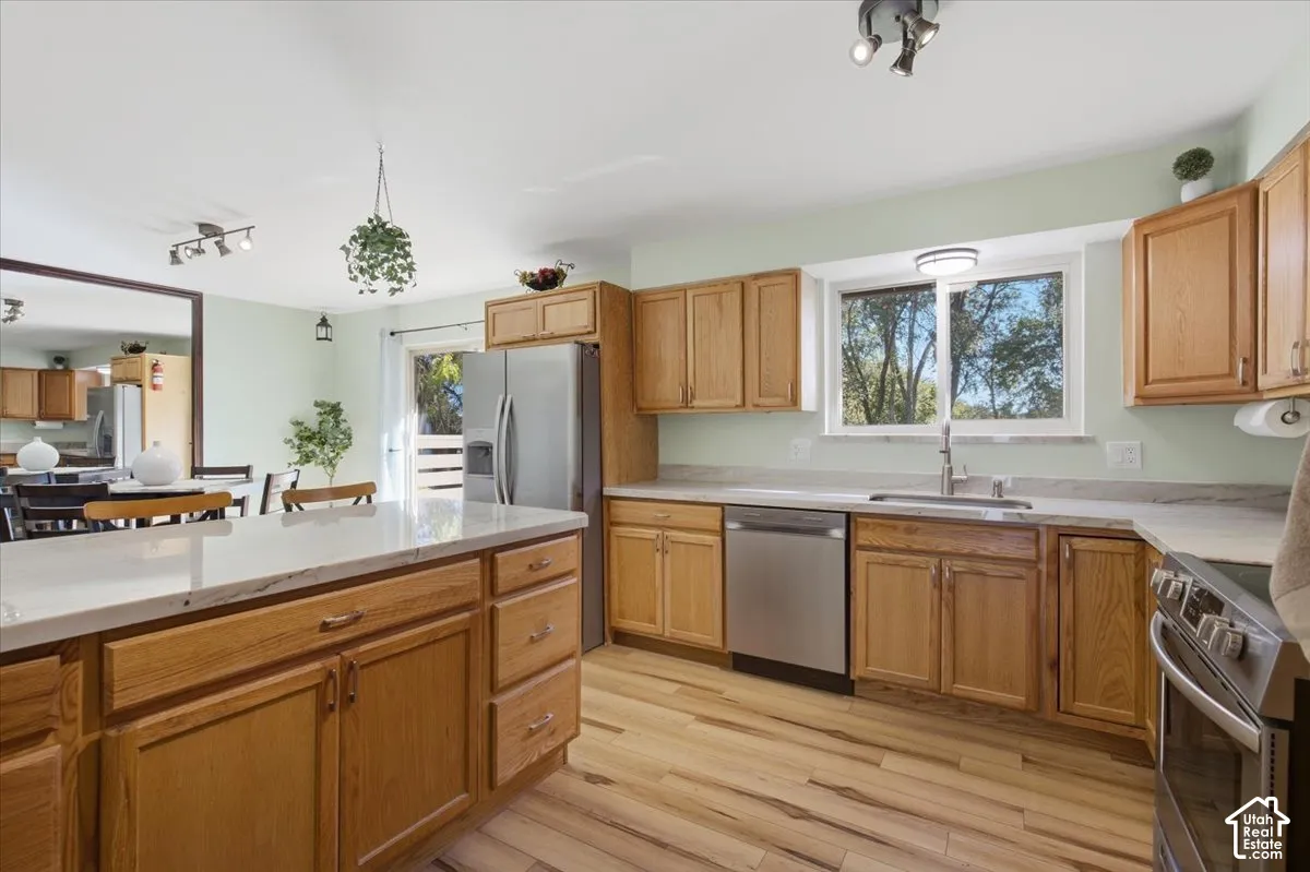 Wood-finish flooring throughout, stainless steel appliances, light-toned cabinetry, light-toned countertops, and a sliding glass door