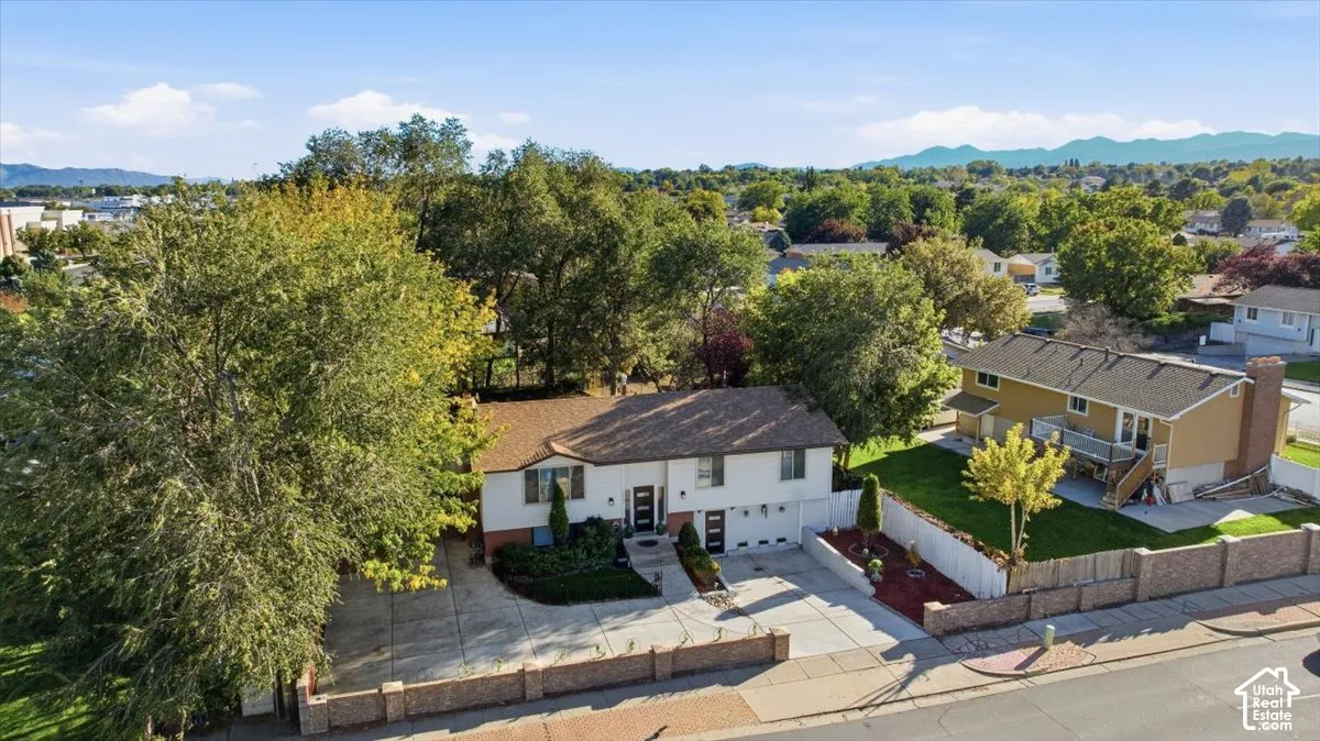 Two-story residence with a brown shingle roof, attached garage, and mature landscaping