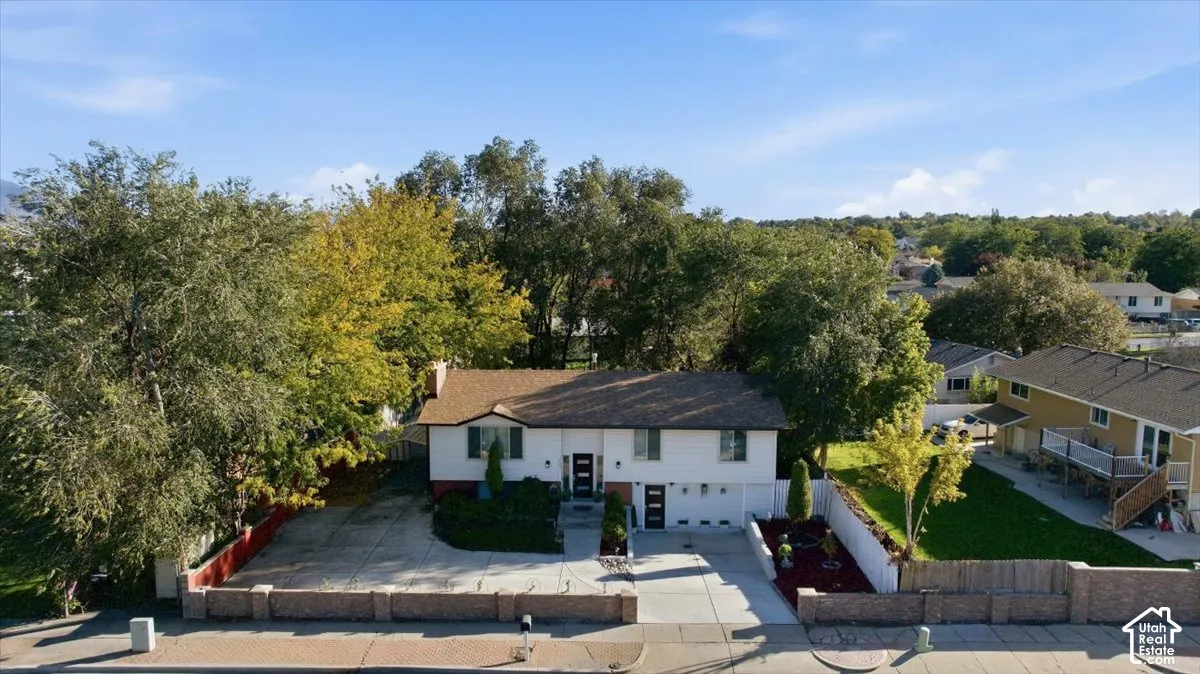 Split-level residence featuring a two-car garage, mature trees, and an established front yard
