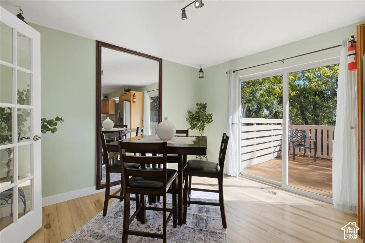 Light wood-finish flooring, a full-length wall mirror, and a glass-paneled entry door enhance this dining area
