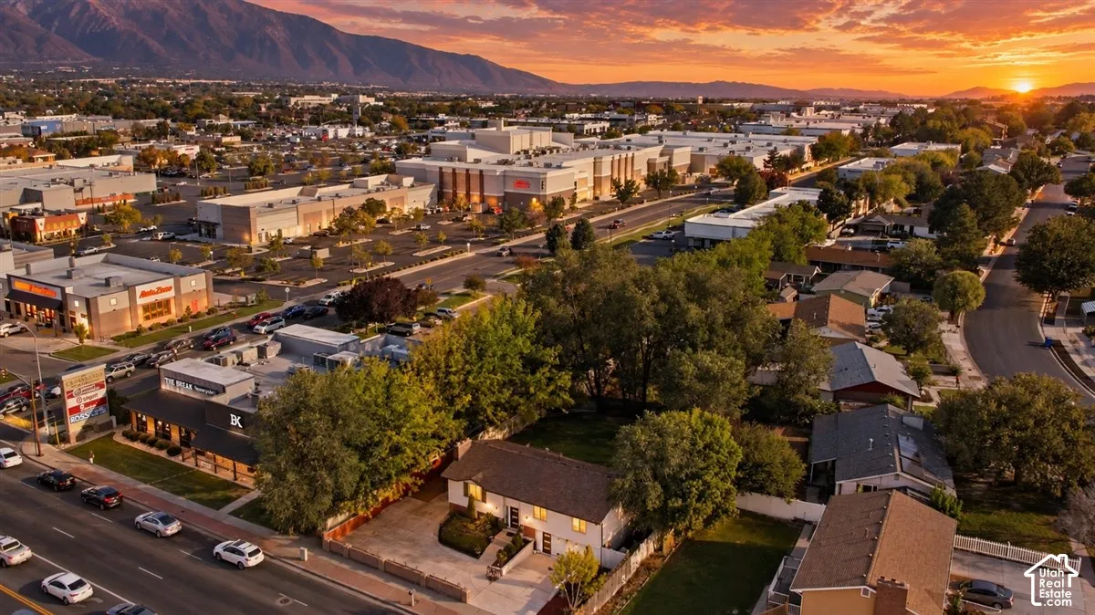 Residential properties surrounded by commercial developments, mature trees, and a mountain backdrop