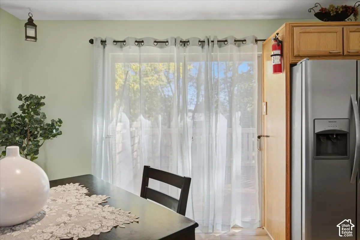 Sliding glass door, light wood cabinetry, stainless steel refrigerator, and light-toned walls