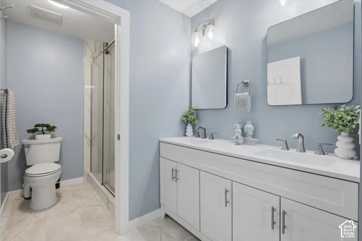 Dual vanity with white cabinetry and integrated sinks, individual rectangular mirrors, and a glass-enclosed shower