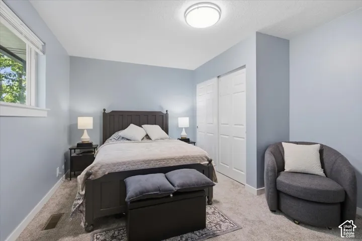 Wall-to-wall carpeting, window with trim, double sliding closet doors, and recessed lighting
