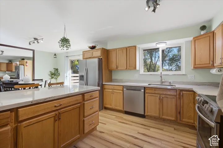 Wood-finish flooring throughout, stainless steel appliances, light-toned cabinetry, light-toned countertops, and a sliding glass door