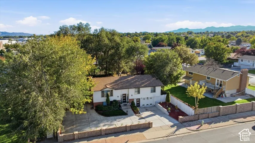Two-story residence with a brown shingle roof, attached garage, and mature landscaping