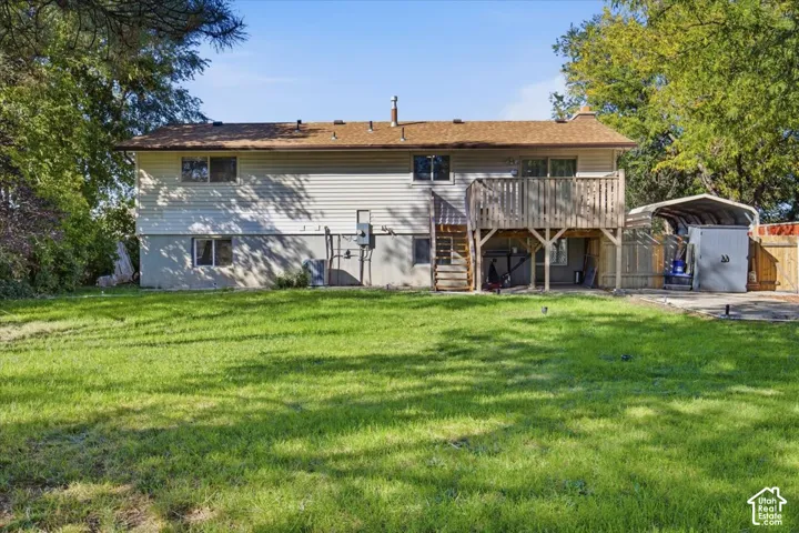 Spacious backyard with a wood deck, shed, and covered carport structure