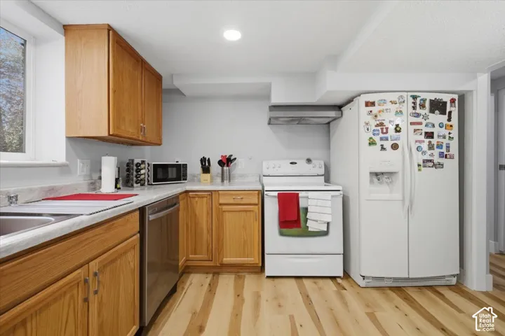 Hardwood-finish flooring, light wood cabinetry, white countertops, stainless steel dishwasher, and recessed lighting