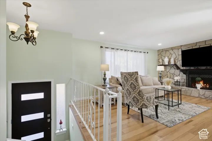 Stone-clad fireplace with mantel shelving, wood-finish flooring, and recessed lighting