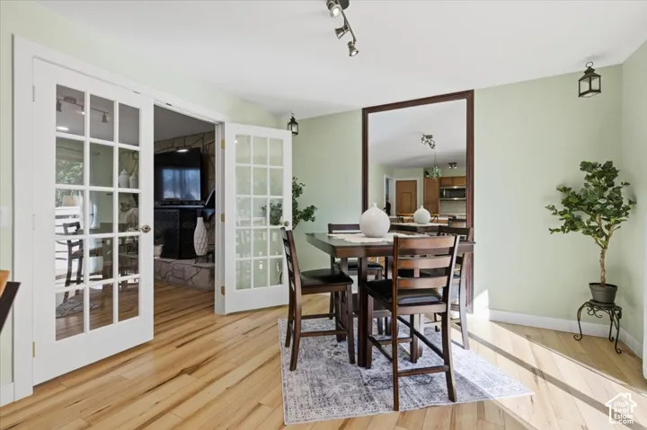 Hardwood flooring, French doors with glass panes, track lighting, and a prominent wall mirror