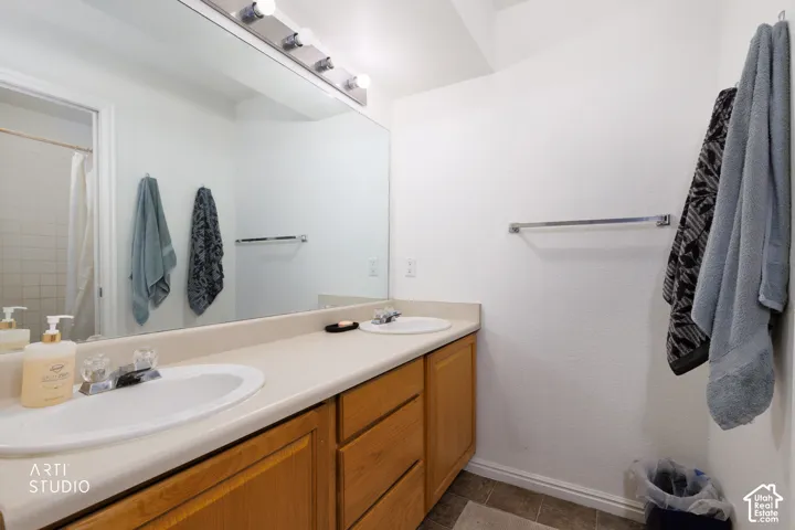 Double vanity with integrated sinks, wood-finish cabinetry, and overhead bar lighting
