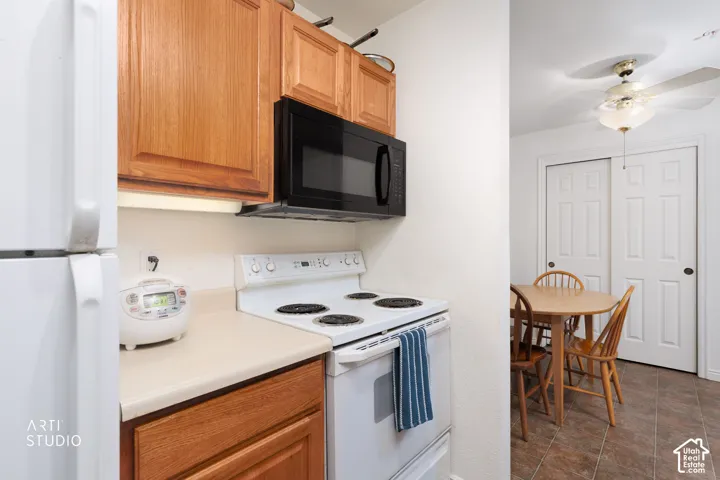 Kitchen area featuring wood-finish cabinetry, white appliances, and a built-in microwave