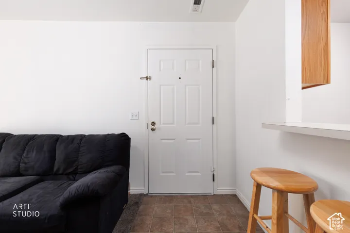White paneled door with a peephole, light wood-finish cabinetry, and a white counter surface