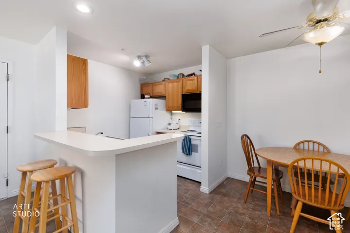 Kitchen featuring light wood cabinetry, white appliances, and a breakfast bar