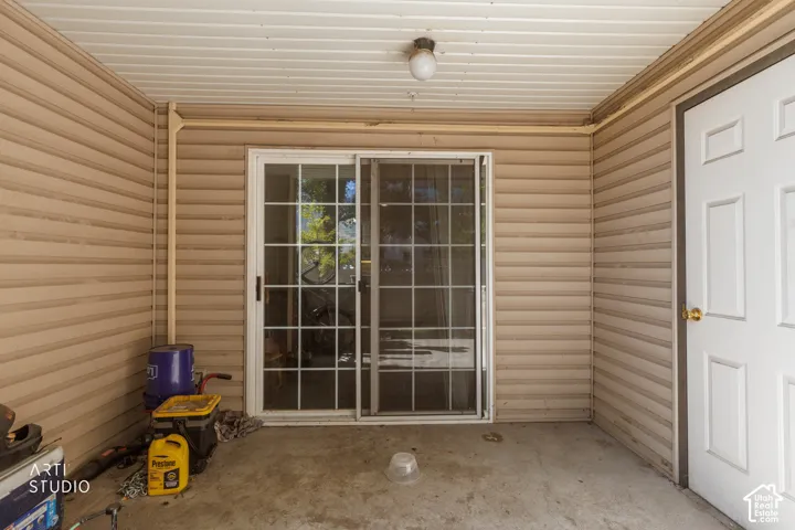 Sliding glass door with grid details, concrete flooring, exterior siding, and a paneled door