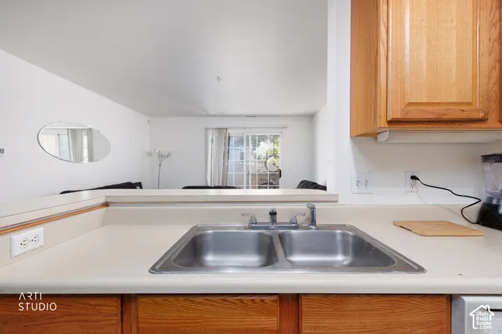 Kitchen featuring a double stainless steel sink, light-colored countertops, and wood cabinetry