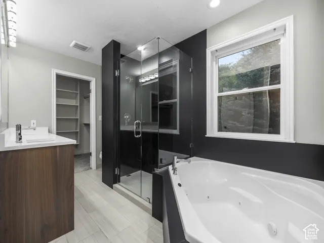 Dual vanity with undermount sinks, glass-enclosed shower, built-in jetted tub, and wood-finish cabinetry