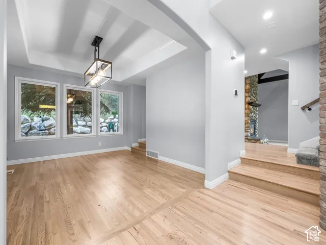Hardwood flooring, three large windows, a tray ceiling, and a contemporary linear chandelier