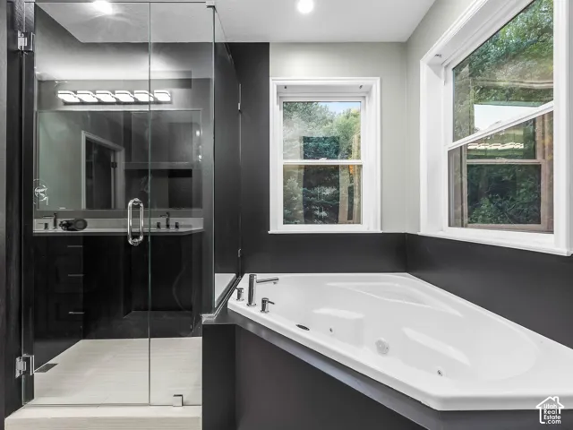 Spacious bathroom with a built-in soaking tub, dual windows, and a separate glass-enclosed shower