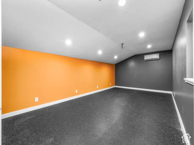 Recessed lighting, sloped ceiling, rubber flooring, and wall-mounted climate control unit
