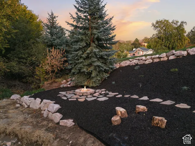Terraced landscaping featuring a stone-lined fire pit, natural stone steps, and dark ground cover