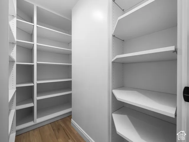 Expansive closet system featuring multiple white built-in shelves and wood-finish flooring