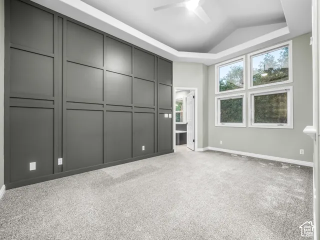 Accent wall with panel molding, tray ceiling, recessed lighting, ceiling fan, and carpet flooring