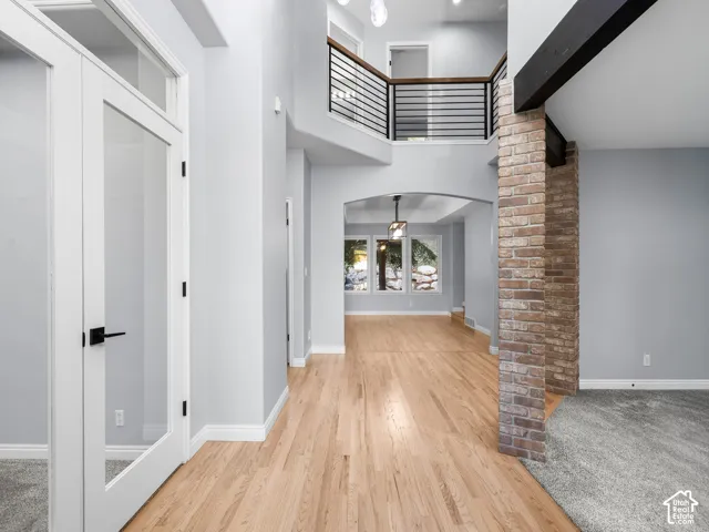 Two-story foyer with a natural wood-finish flooring, a brick-clad column, and a balcony with metal and wood railing