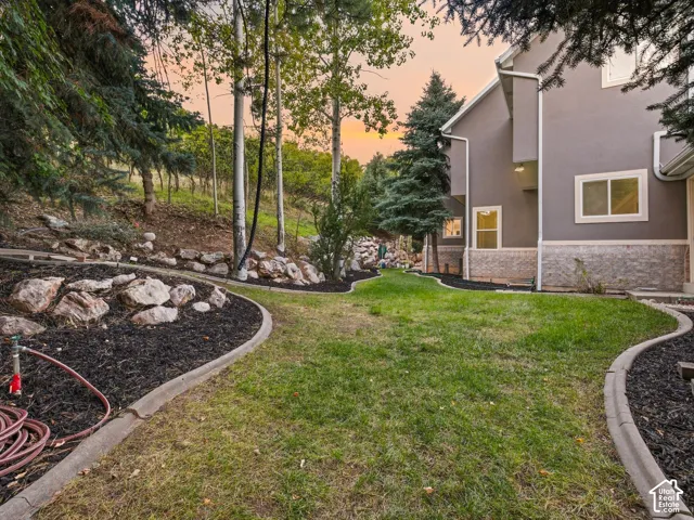 Landscaped grounds featuring a manicured lawn, established trees, decorative rock arrangements, and dark ground cover