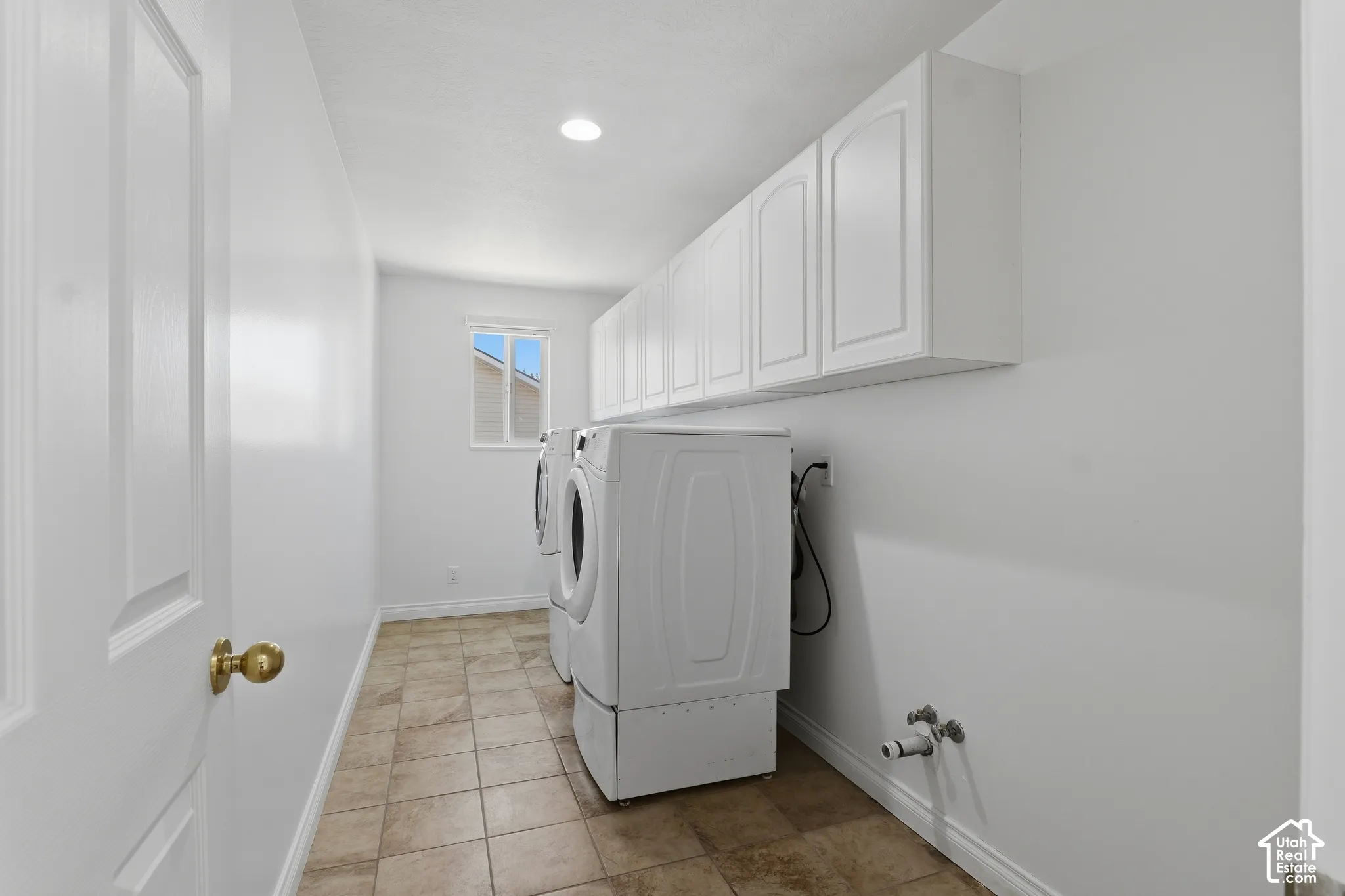 Laundry area featuring tile flooring, white cabinetry, a window, and recessed lighting