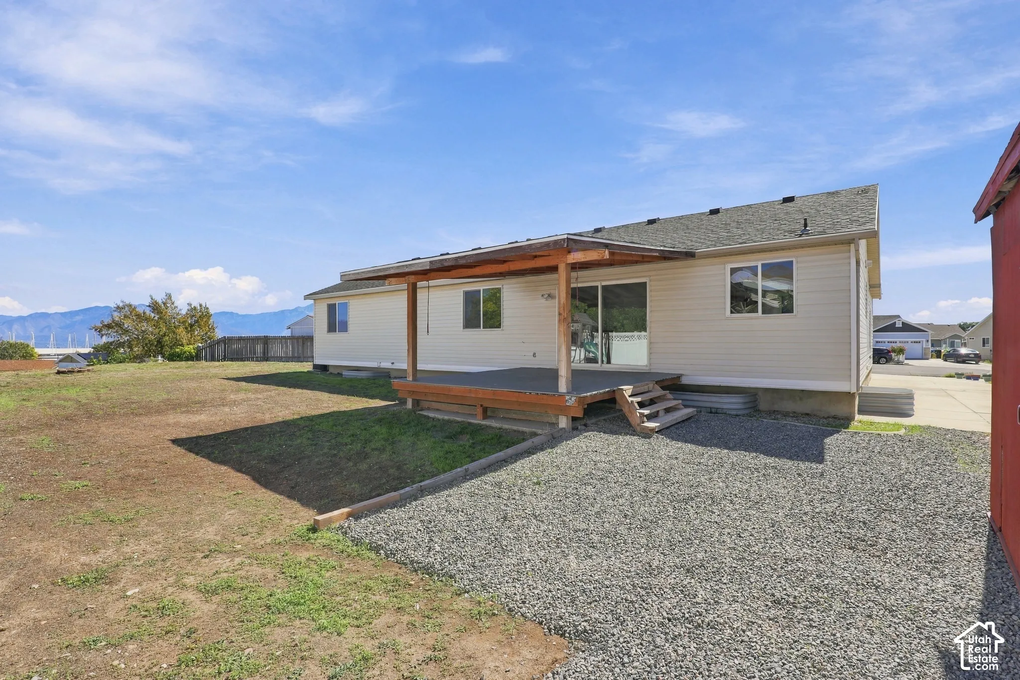 Covered outdoor deck with steps, gravel ground cover, and a partial red shed