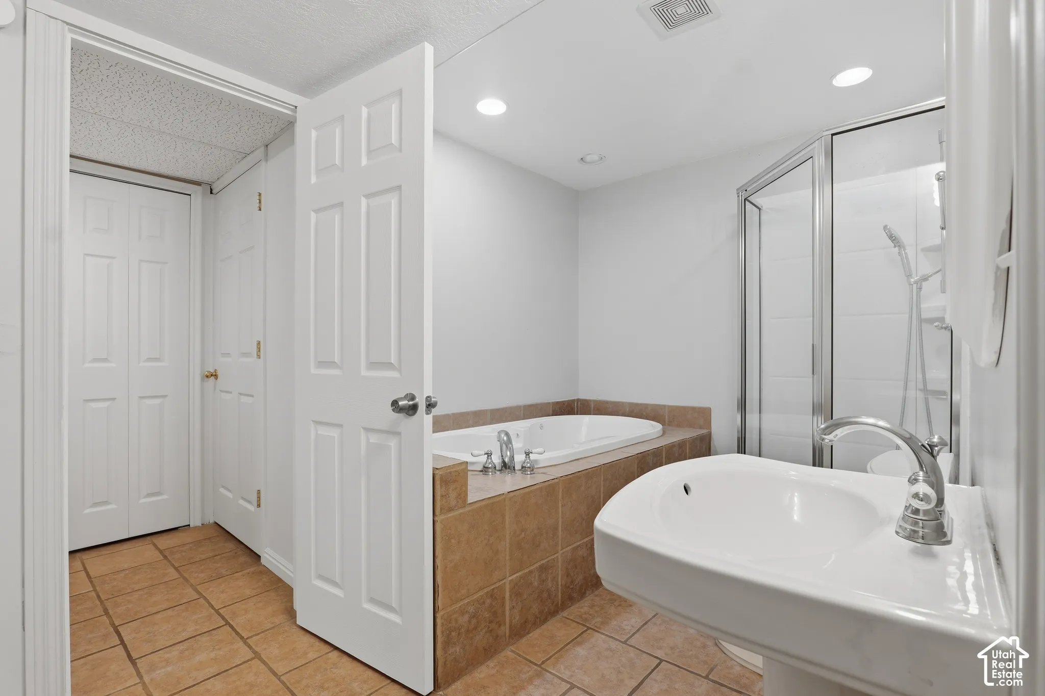 Pedestal sink with chrome faucet, walk-in shower with glass enclosure, built-in bathtub, and ceramic tile flooring