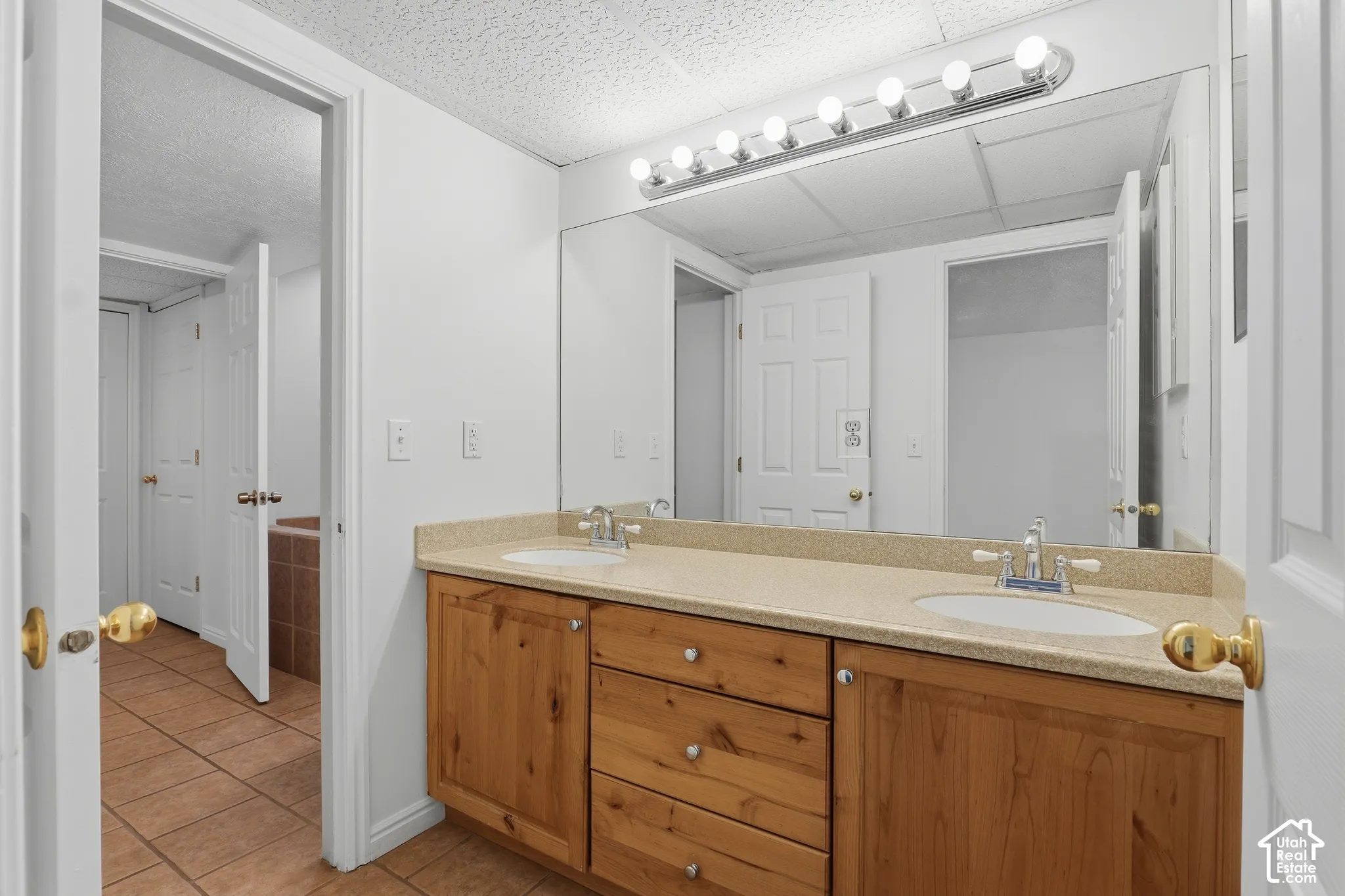 Double vanity with integrated sinks, wood-finish cabinetry, and a large wall-mounted mirror