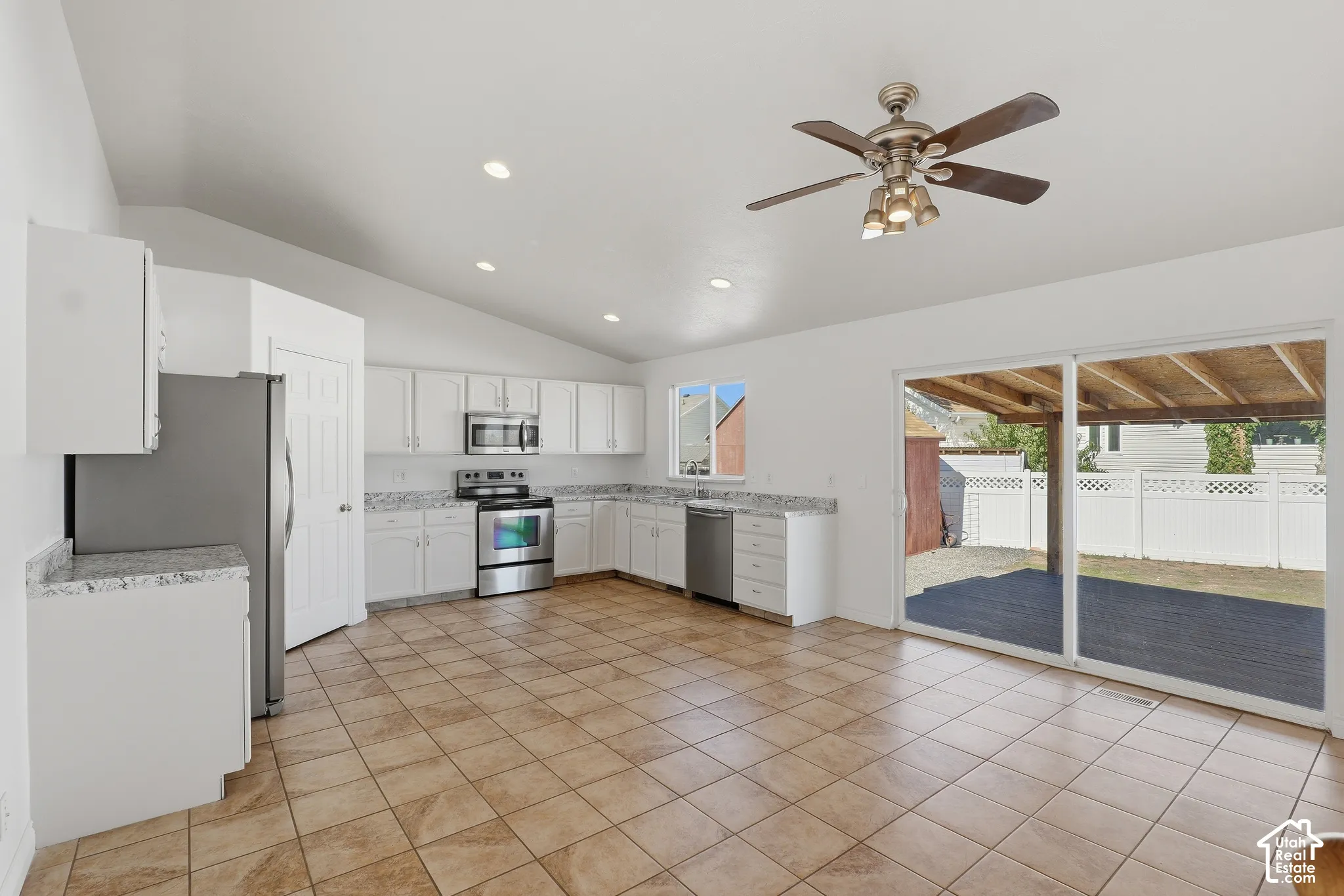 Kitchen featuring white cabinetry, stainless steel appliances, granite-look countertops, and tile flooring