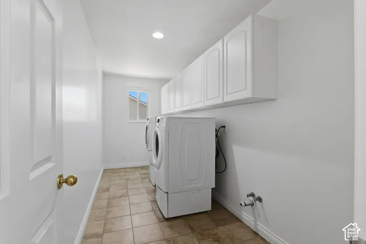 Laundry area featuring tile flooring, white cabinetry, a window, and recessed lighting
