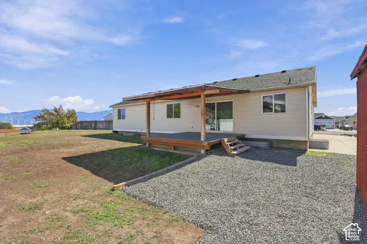 Covered outdoor deck with steps, gravel ground cover, and a partial red shed