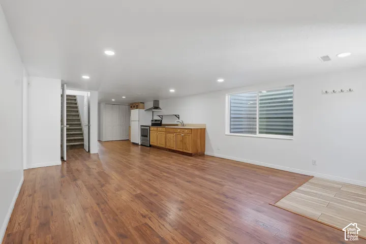 Open concept living area featuring, recessed lighting, a full-size window, and a kitchenette with wood cabinetry and appliances